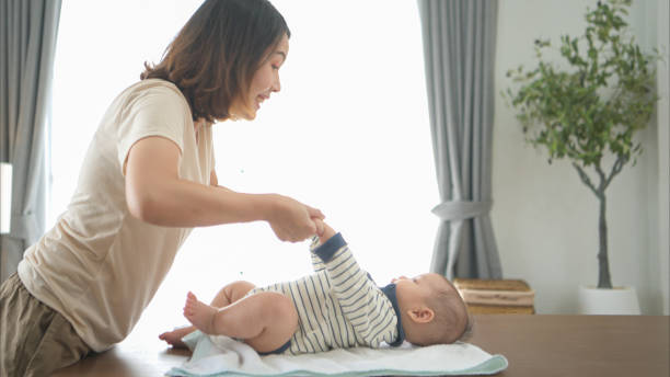 istock A tiny boy is getting ready to have a bath and mother helps raise to sit 2165166430