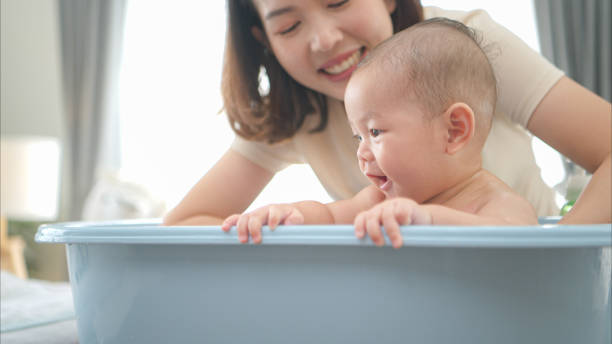 istock A tiny child enjoys taking a bath in a baby bathtub with mom 2165166436