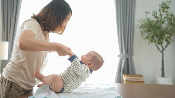 istock A tiny boy is getting ready to have a bath and mother helps raise to sit 2165166583