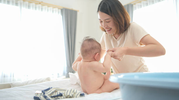 istock A tiny boy is getting ready to have a bath and mother helps raise to sit 2165166646