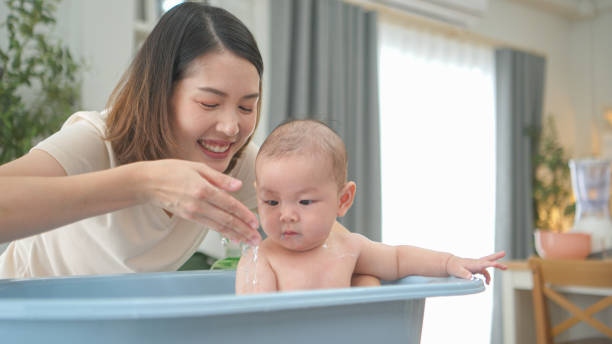 istock A tiny child enjoys taking a bath in a baby bathtub with mom 2165166660