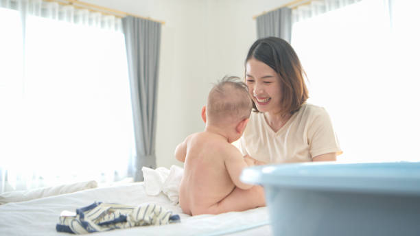 istock A tiny boy is getting ready to have a bath and mother helps raise to sit 2165166672