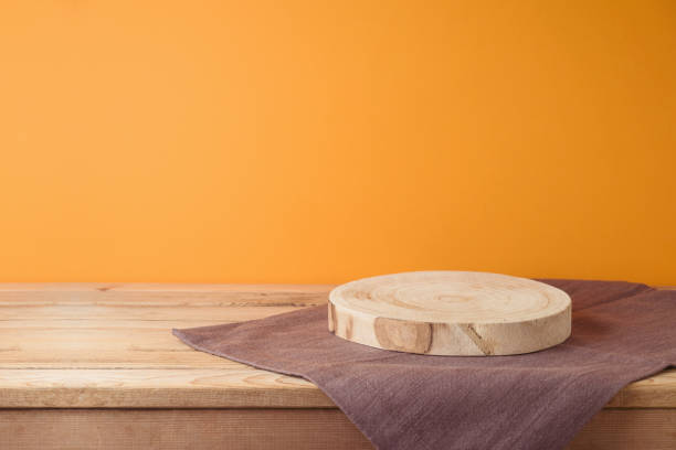 istock Empty log podium with tablecloth on wooden table over orange wall background. Halloween mock up for design and product display. 2165167594
