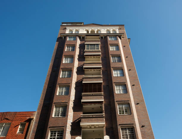Part of a tall brick apartment building on a clear, sunny morning.