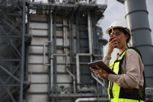 istock A female energy engineer is utilizing a tablet and walkie talkie while operating within a medium-sized power plant situated in an industrial estate. 2165172345