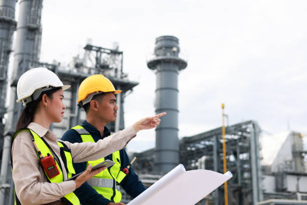 istock Two electrical engineers work with blueprints at a middle-sized power plant in an industrial estate. Power Industry, Power Plant Manufacturing 2165179717