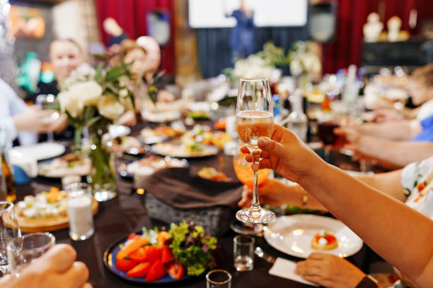 hands with glasses. A served banquet table with a bouquet of flowers and a black tablecloth. catering for holidays.