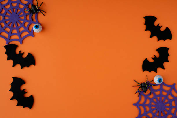 istock Bats, cobwebs, spiders and chocolate eyes decorating an orange background. 2165196771