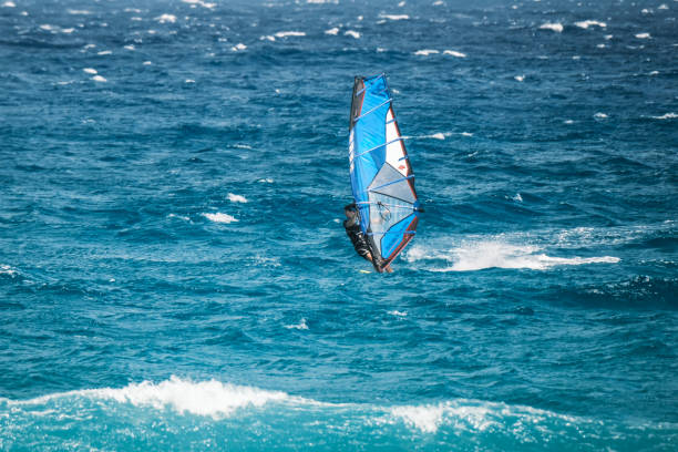 Algajola, Corsica, France - 31st May 2024: A windsurfer tackles strong waves off Aregno Plage at Algajola on the coast of the Mediterranean island of Corsica