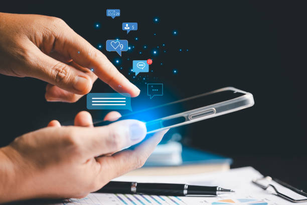 istock Person using smartphone taps on social media icon, initiating chat and communication within their network. chat, social, communication, icon, media, message, Concept central to modern messaging. 2165201267