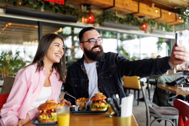 istock Happy young couple taking selfie while having lunch in local burger bar 2165202230