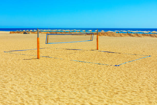 Volleyball net is set up on a sandy beach. Volleyball net on coast with ocean in background