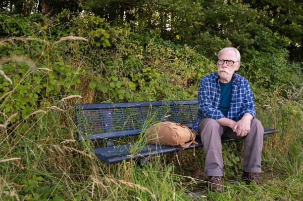 istock Mature man sitting on a bench taking time out 2165209167