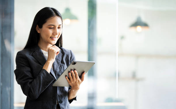 istock Asian  businesswoman CEO holding digital tablet using fintech tab application standing at workplace in office. 2165210909