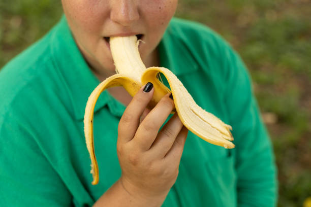 a little girl eating a banana isolated on white.