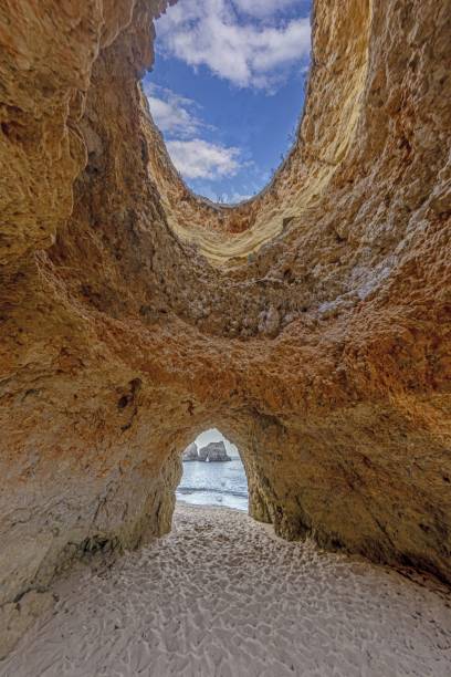 istock a man walking into the ocean through an opening in the rocks 2165213748