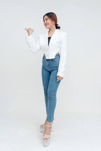 istock A smiling and kind young woman looking sideways while gesturing to her left side with her thumb. Isolated on a white background. 2165217685