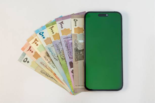Syrian currency notes and Smartphone with green blank screen isolated on white background