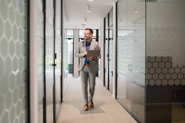 istock Full length of confident male engineer programming over computer while walking in office corridor 2165225170