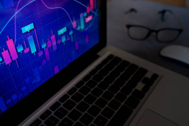istock Laptop displaying a trading graph with glasses on the table 2165225197