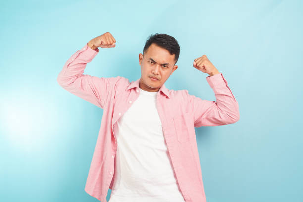 Strong man gesture with pink shirt standing on blue background