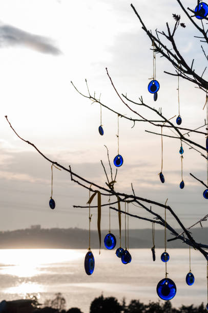 Evil eye beads against a sunset on the Bosphorus straits hanging ifrom the braches of a tree in Istanbul