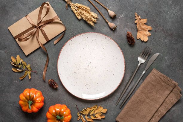 istock Autumn table setting on dark background. Empty white plate, cutlery, linen napkin and autumn decor. Top view, flat lay. 2165227295