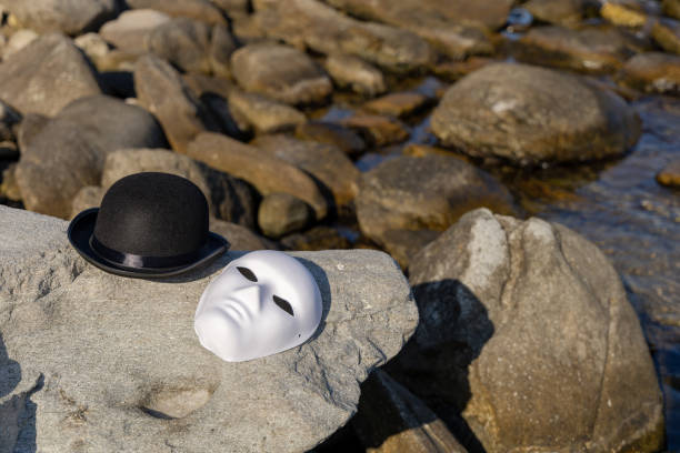 Bowler cap and face mask on sea rock