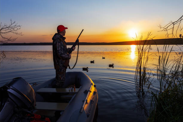 istock Duck hunter with rifle hunting ducks at sunrise. 2165242168