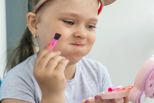 istock Adorable little girl applying makeup using children's cosmetics 2165245591