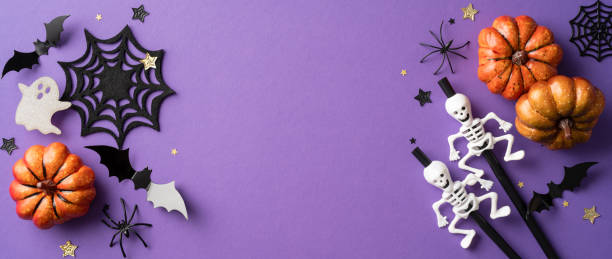 istock Halloween background with pumpkins, skeletons, bats, spiderwebs, and ghost decorations on a purple backdrop 2165250022