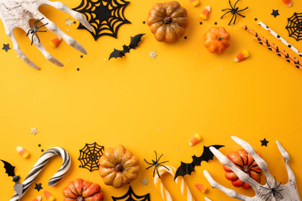 istock Festive Halloween background featuring pumpkins, candy corn, creepy hands, spiders, and candy cane on orange backdrop for seasonal celebration 2165250035