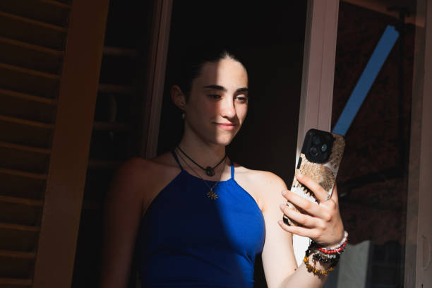 Teenager smiles while is using a smartphone.
