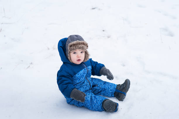 istock Toddler boy 1 year old playing with snow in winter 2165257452
