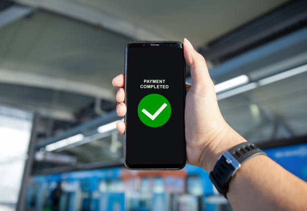 istock hand holding smartphone with payment completed notification checkmark sign on screen on outdoor background 2165259176
