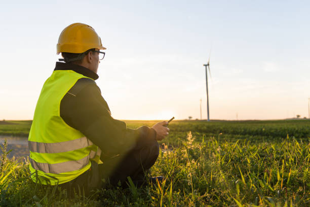 istock Worker sits on the grass and looks at wind turbines 2165260020