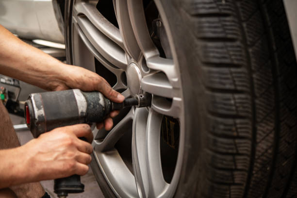 istock Automotive Technician Performing Tire Change with Impact Wrench in Workshop Environment 2165260437