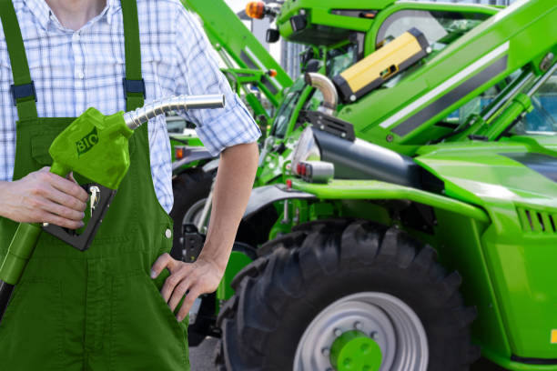 istock Man with biofuel refueling nozzle next to agricultural machines. 2165260451