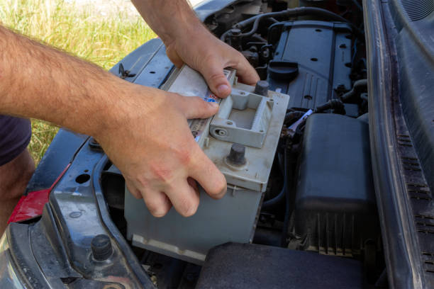istock the hands of a man removing a faulty car battery from a car 2165264607
