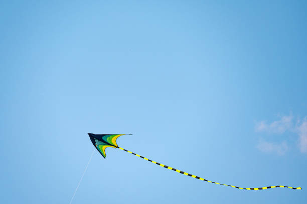 istock A bright green kite with a long tail hovers in the blue sky. A copy space 2165265722