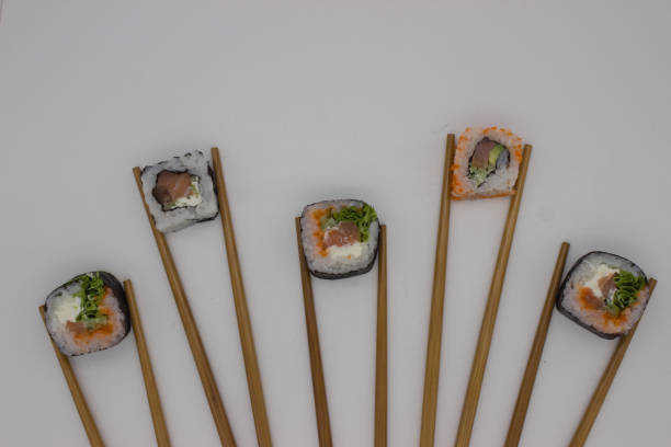 A Tobiko Roe Sushi being held by wooden chopsticks