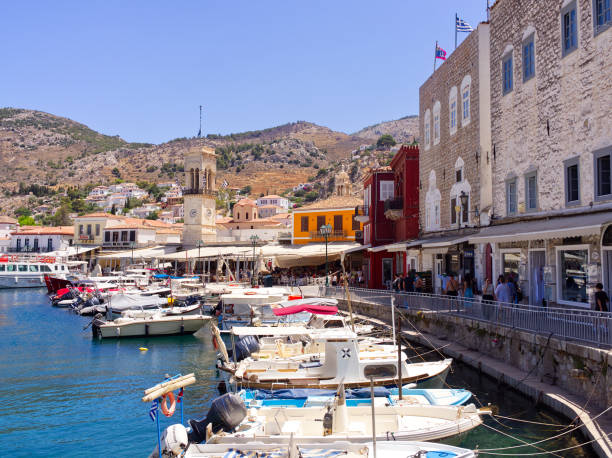 Hydra island, Greece - June 23, 2024: Picturesque port view with boats and church tower in a sunny summer day