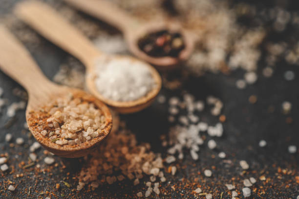 Wooden spoons with different spices on a black background, banner.