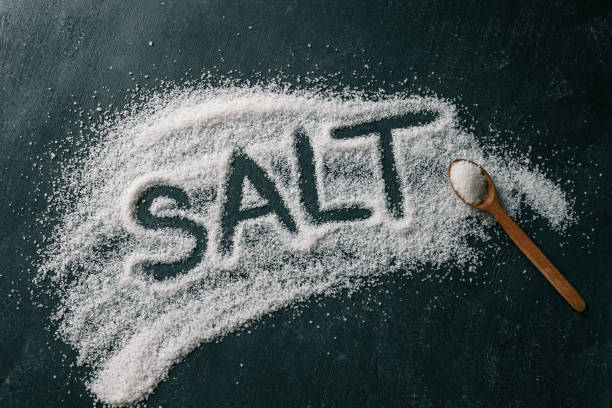 istock Heap of white salt on dark background with text SALT 2165271223