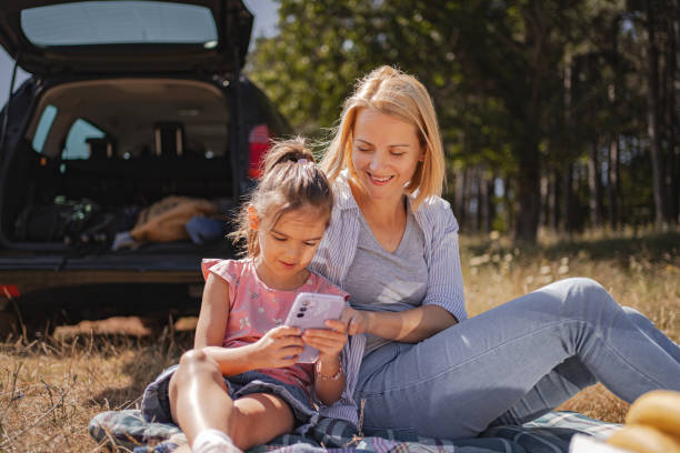 istock Mother and daughter using mobile phone while relaxing in nature on a sunny day 2165272954