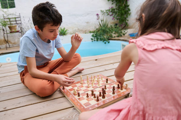 istock Children playing chess outside near pool on a wooden deck 2165276802