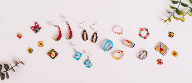 istock Earrings, rings and toys woven from multi-colored beads on a pink background top view web banner 2165281388