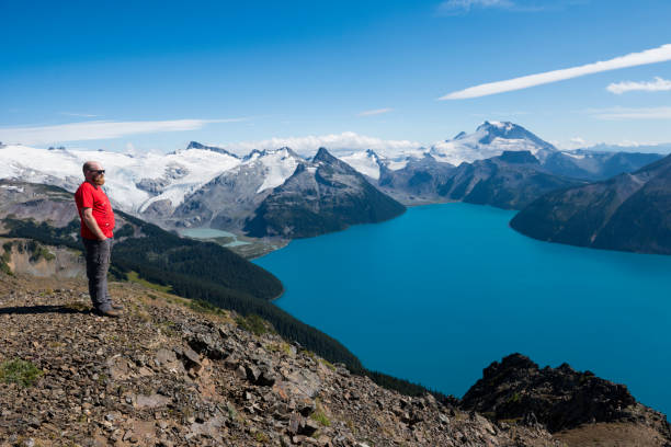 istock Man hikes above lake and mountains 2165281807