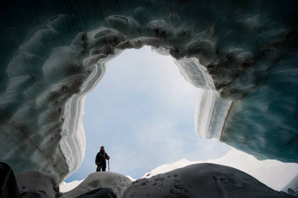 istock Explorer stands in mouth of ice cave 2165283272