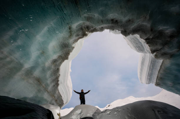 istock Explorer stands in mouth of ice cave 2165283274